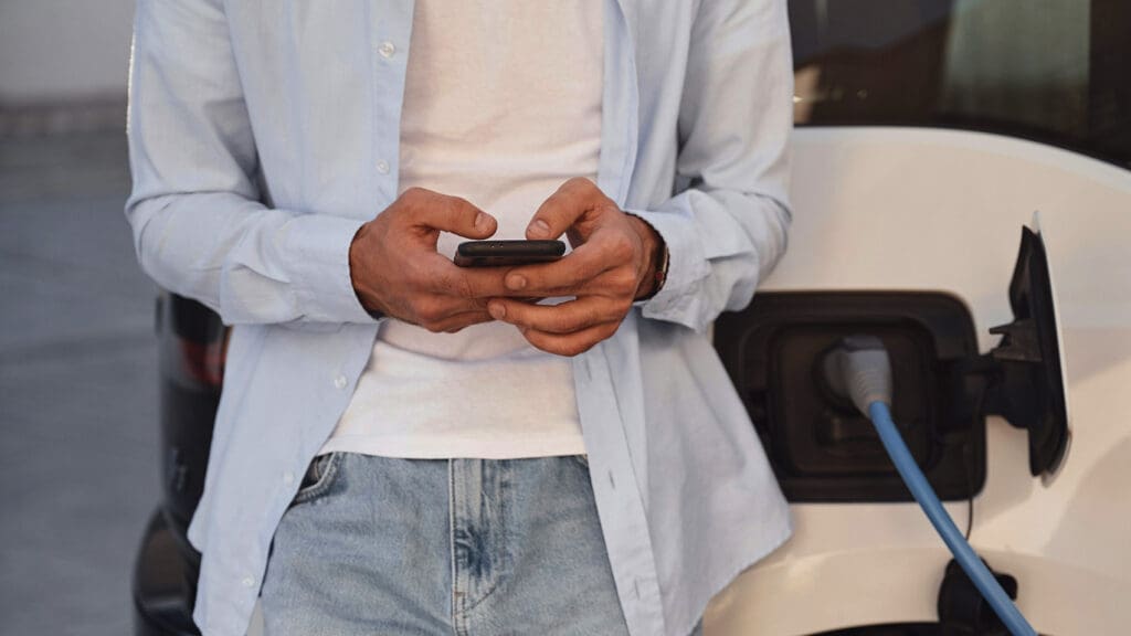 Man tittar på sin telefon vid en laddbox i en brf